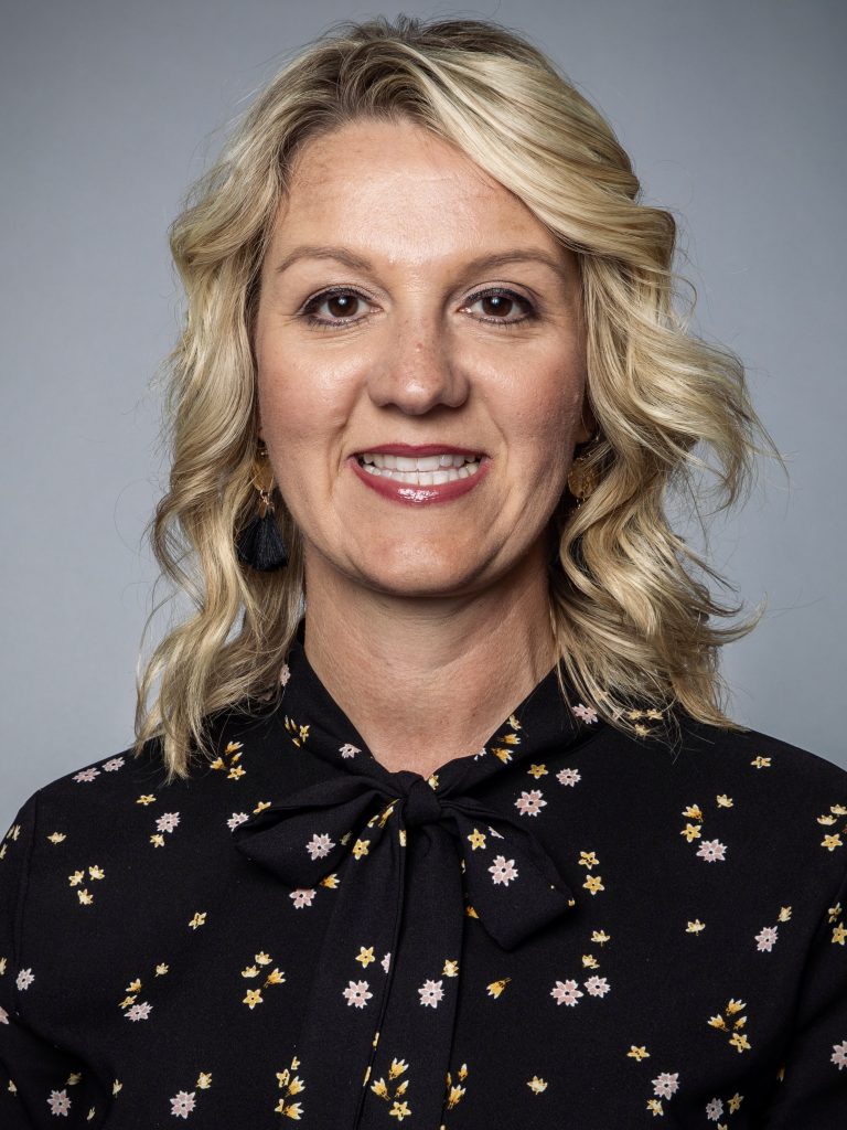 Andy Hayes, a smiling white woman with medium-length wavy blond hair and a dark shirt.