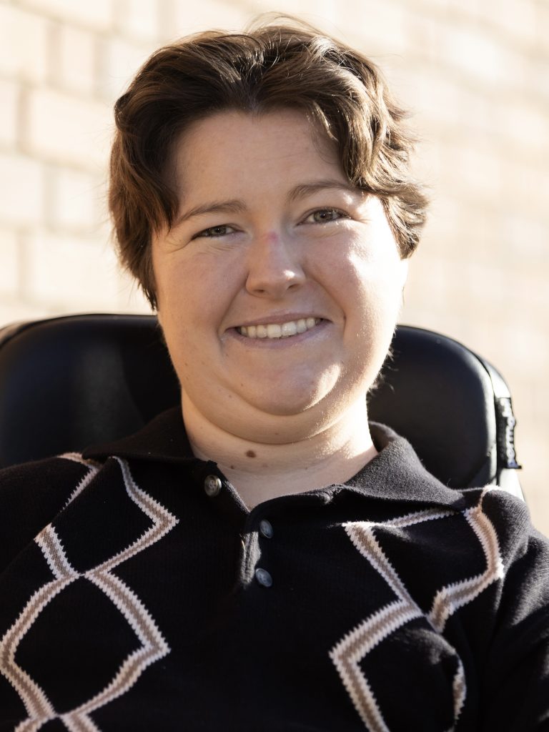 Ellie Stitzer, a smiling white woman with short wavy brunette hair and a dark shirt.