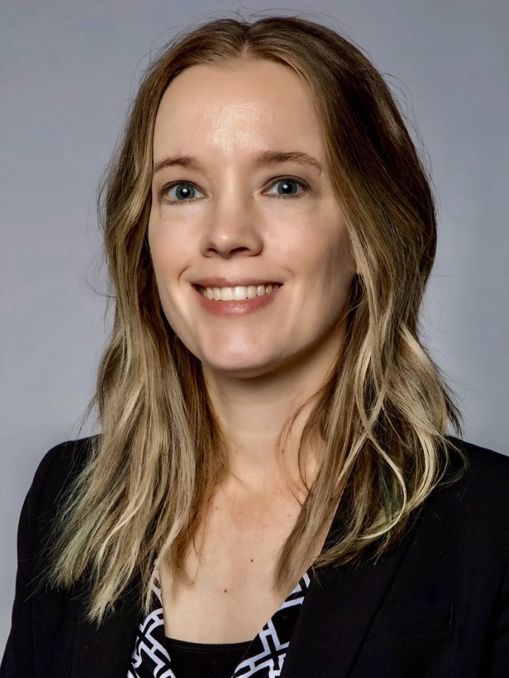 Mindy Wirges, a smiling white woman with medium-length wavy blond hair and dark shirt with a blazer.